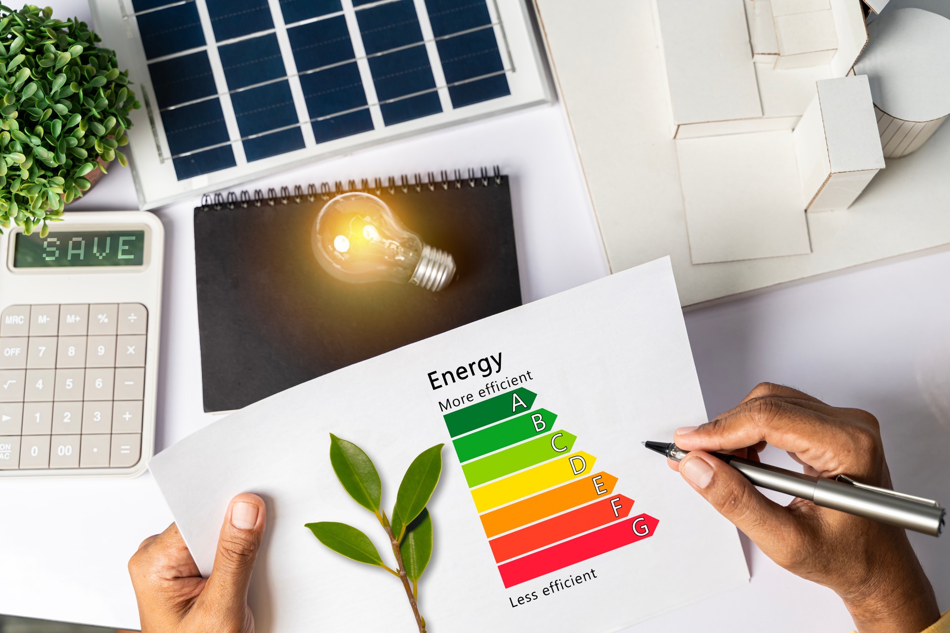 Energy efficiency concept with energy level chart Tabletop energy efficiency graph with house diagram calculator Solar panels. Businessman planning to use energy.